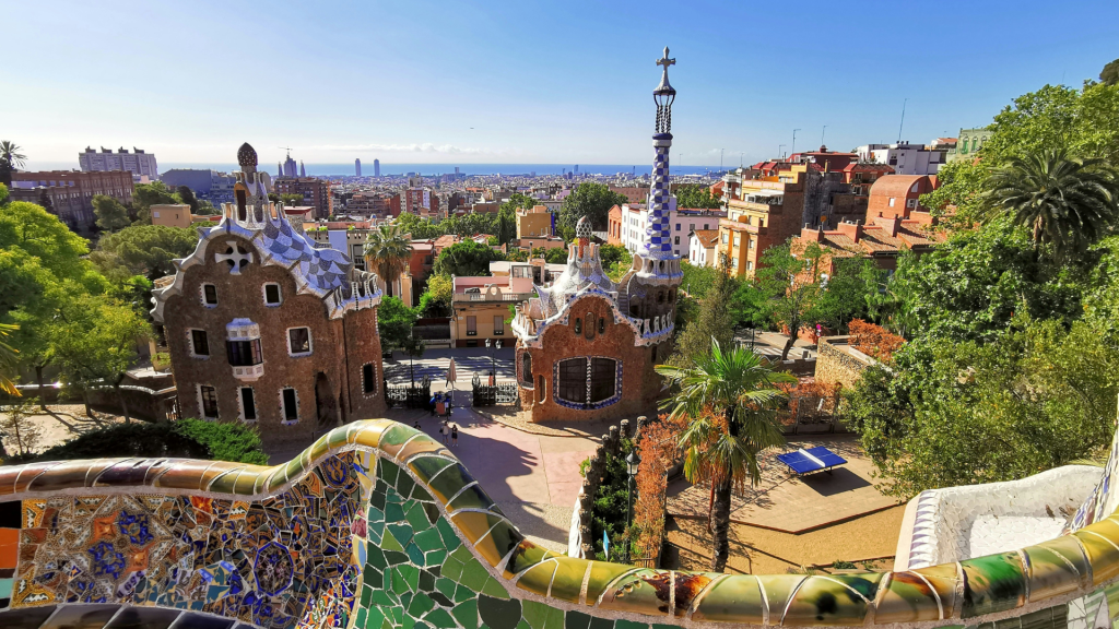 A sunny photo of Park Guell with colourful mosaic tiling in the foreground